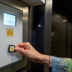Frau hält einen RFID-Chip an den Sensor eines Bedientableau