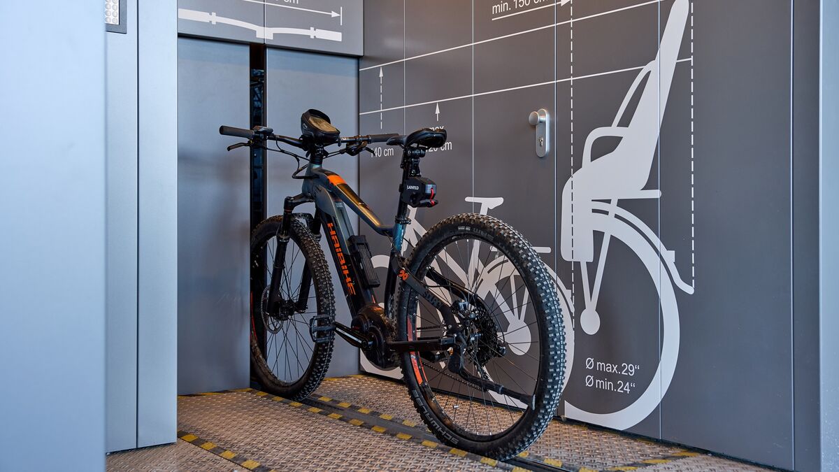A bicycle on a rail in front of an automatic bicycle parking system