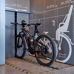 A bicycle on a rail in front of an automatic bicycle parking system