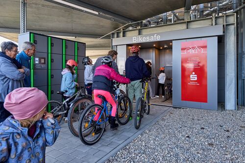 Kinder mit Fahrrädern stehen vor dem Eingang des automatischen Fahrradparksystems