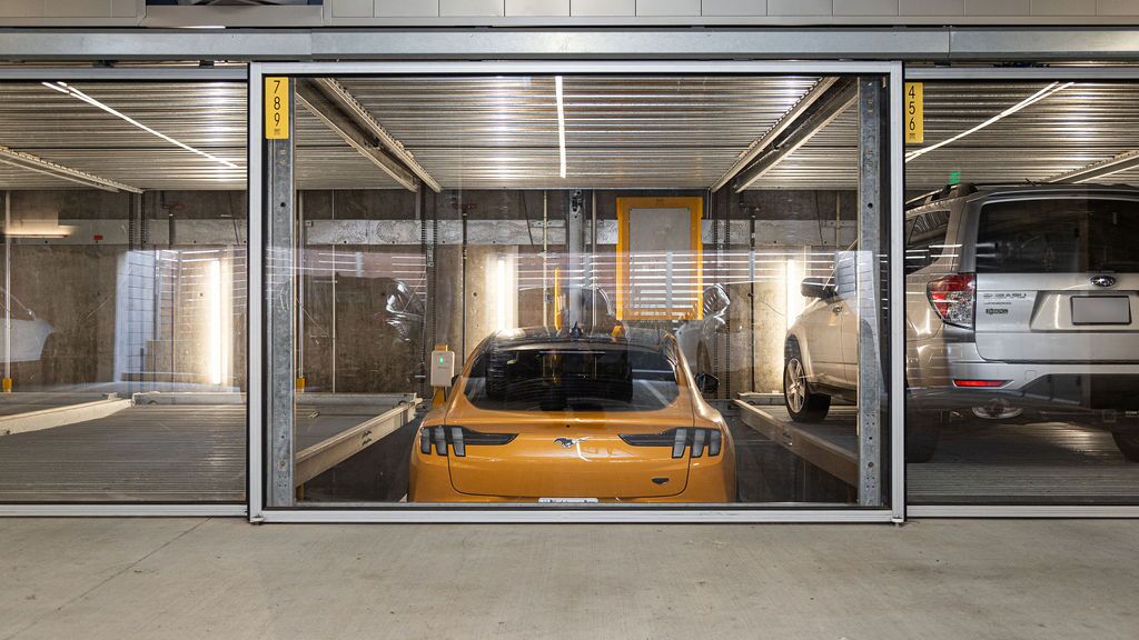 Das Bild zeigt einen gelben Sportwagen in einem Parksystem innerhalb einer modernen Tiefgarage.