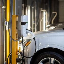 A vehicle is parked on the platform of a parking system and is being charged via the integrated charging facility for electric vehicles.