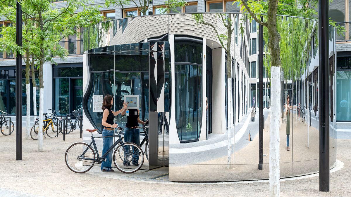 Frau mit Fahrrad bedient einen Monitor am Fahrradparksystem