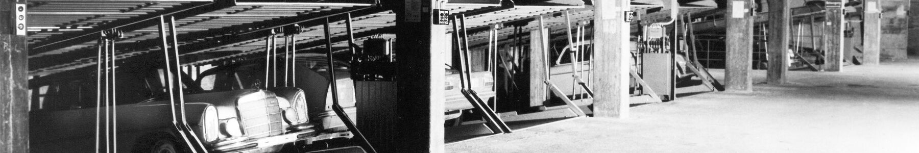 Black-and-white photograph showing old parking systems with cars parked in them