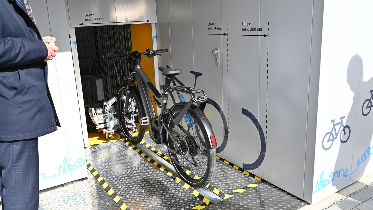 Fahrrad auf einer Radschiene vor einem automatischen Fahrradparksystem
