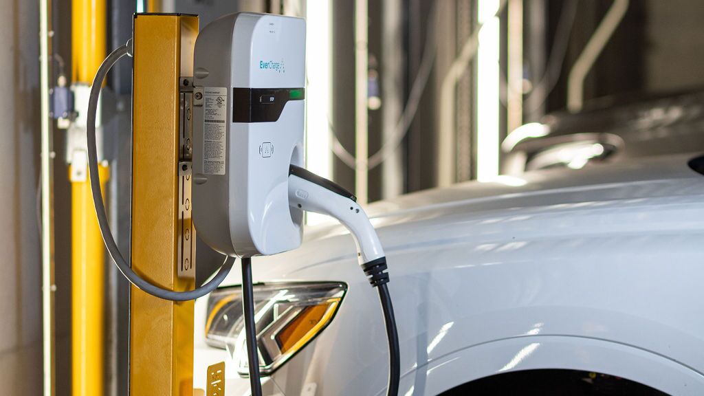A vehicle is parked on the platform of a parking system and is being charged via the integrated charging facility for electric vehicles.
