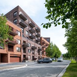 Moderne Wohnanlage, bei der ein Fahrzeug in eine Garage mit integriertem Parksystem fährt.