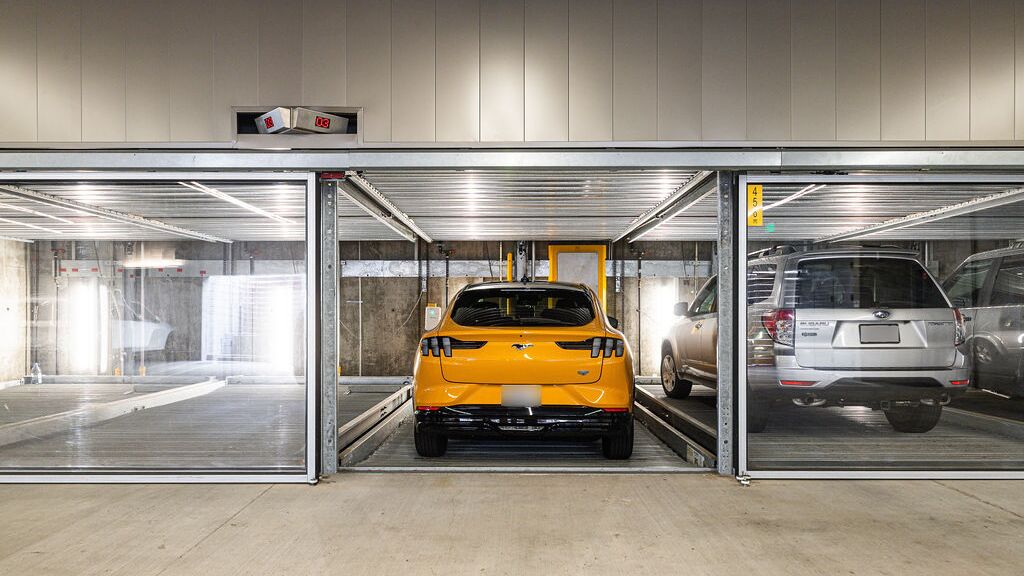 Das Bild zeigt eine moderne Tiefgarage mit mehreren verglasten Stellplätzen eines Parksystems.