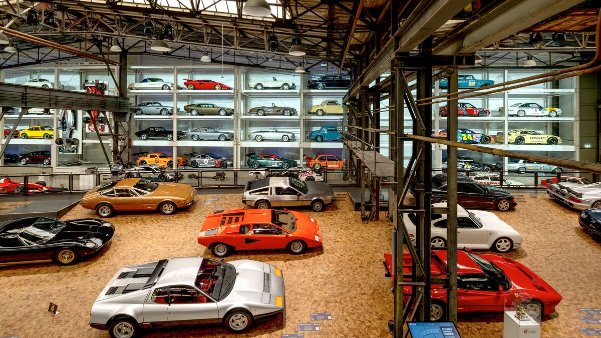 A wall-mounted shelf full of cars in a museum