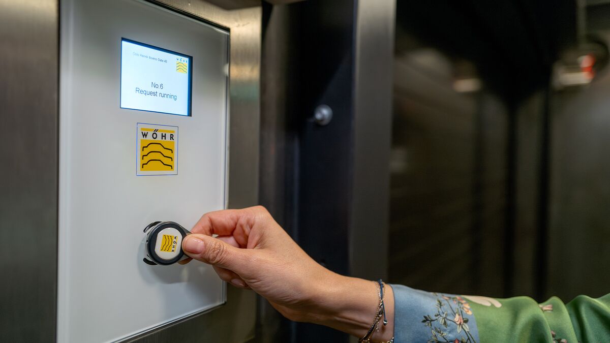 Frau hält einen RFID-Chip an den Sensor eines Bedientableau