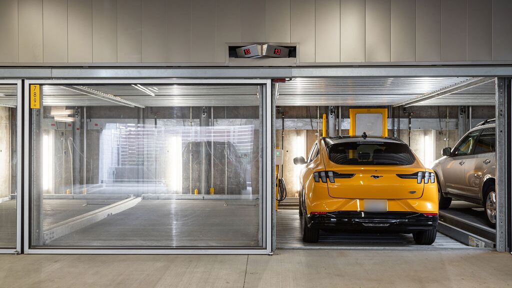 Das Bild zeigt mehrere Fahrzeuge in verglasten Stellplätzen eines Parksystems in einer modernen Tiefgarage.