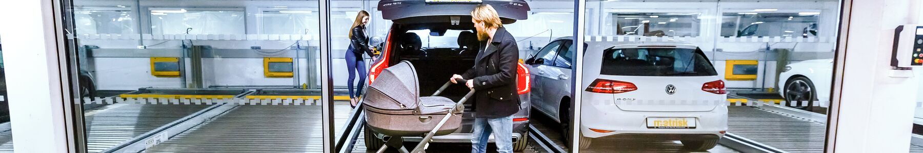Parksystem mit parkenden Autos und einer Person mit Kinderwagen