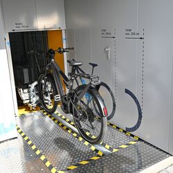 Fahrrad auf einer Radschiene vor einem automatischen Fahrradparksystem