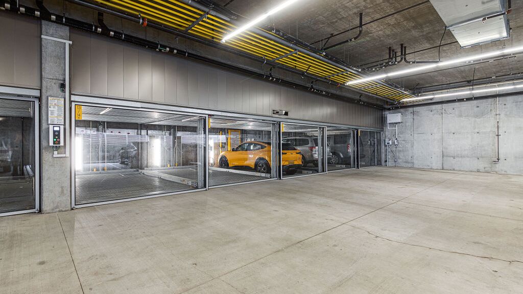 Das Bild zeigt eine moderne Tiefgarage mit mehreren verglasten Stellplätzen eines Parksystems.